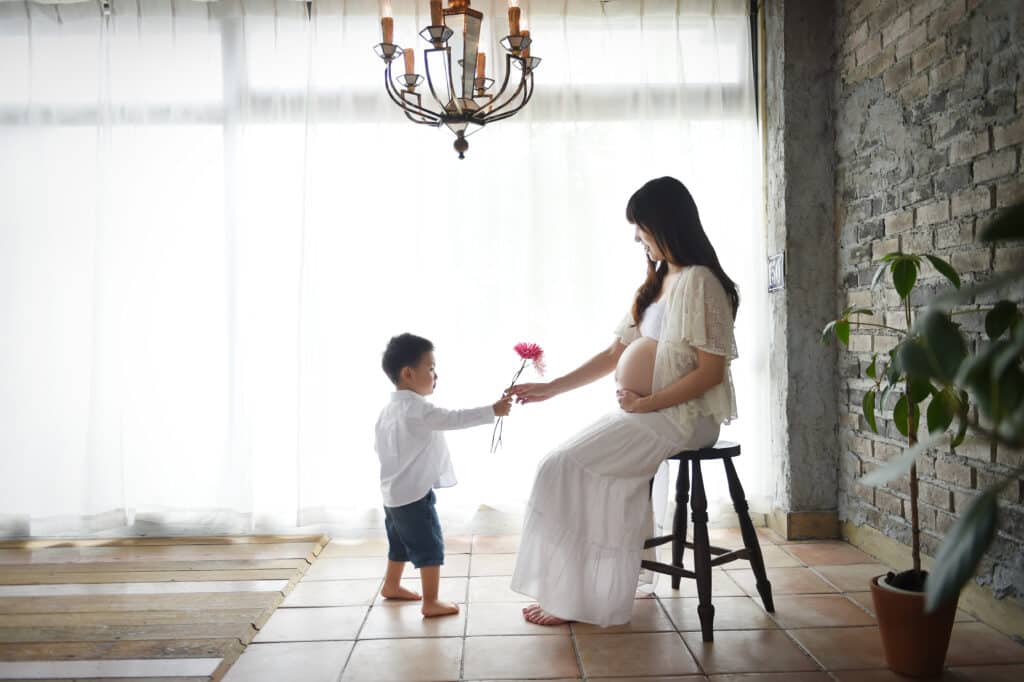 a child giving a flower to a pregnant woman