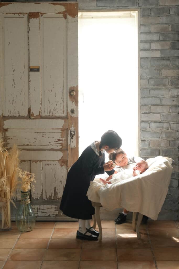 a woman kissing two children in a crib
