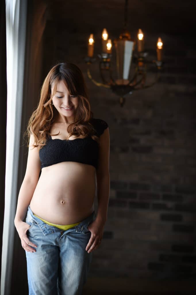 a pregnant woman standing in front of a window