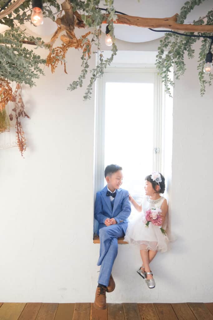 a boy and girl sitting on a window sill